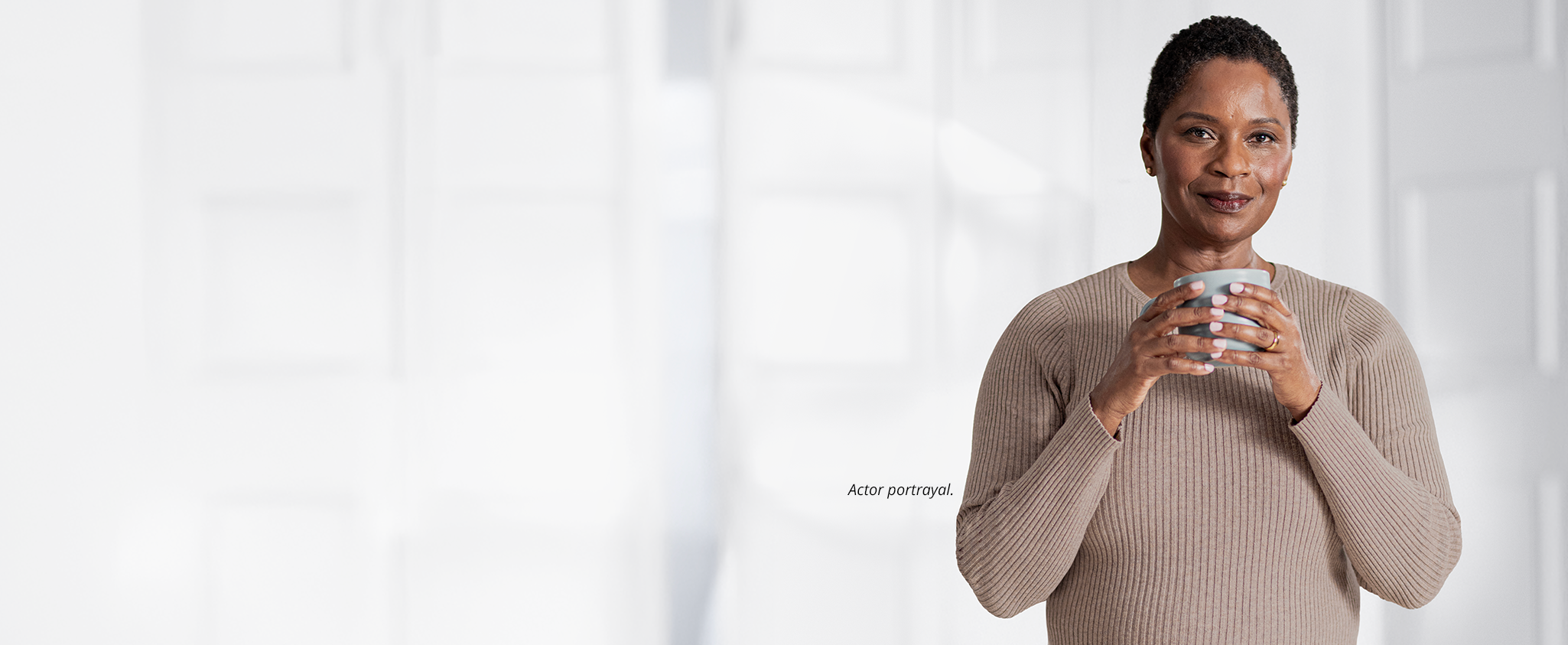 An older woman stands holding a coffee mug. The footnote next to her reads: Actor portrayal.