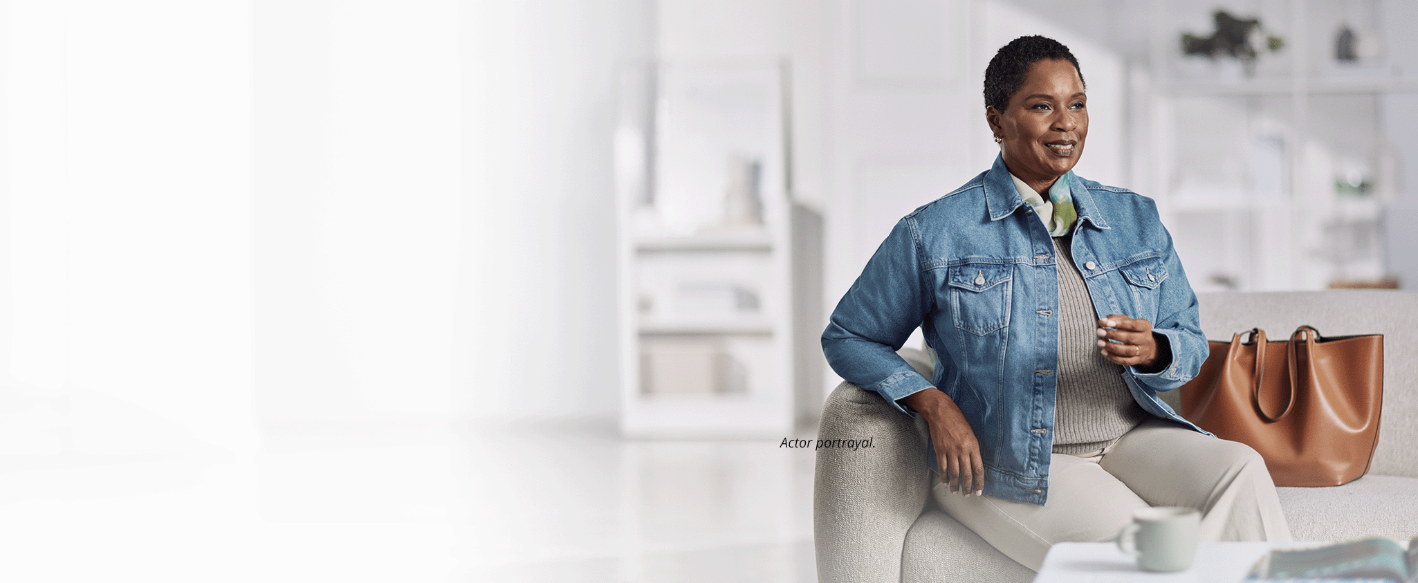 An older woman smiling and sitting on a white couch. The headline next to her says: Financial coverage & support. The footnote next to her reads: Actor portrayal.